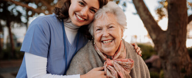 A caregiver and elderly woman smiling together outdoors at a dementia care home in the San Fernando Valley