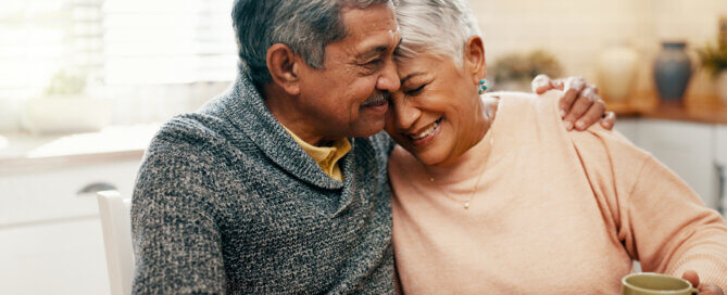 Senior couple smiling together on a couch, representing assisted living for couples with different needs